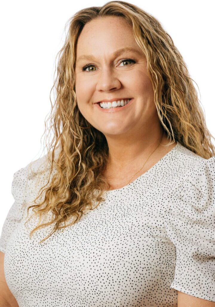 Smiling woman with curly hair and blouse.